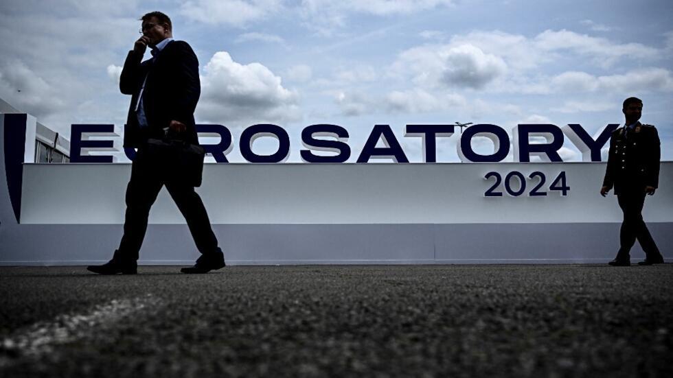 Visitors walk in front of the logo of the Eurosatory international land, air defence and security trade fair, in Villepinte, a northern suburb of Paris on June 17, 2024