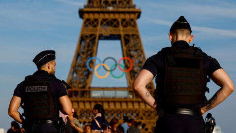 Police officers patrol on the Trocadero square in front of the Olympic rings displayed on the Eiffel Tower, 7 June 2024. Officials and organisers have questions about the security and organisation of the Games in the midst of snap legislative elections in France.