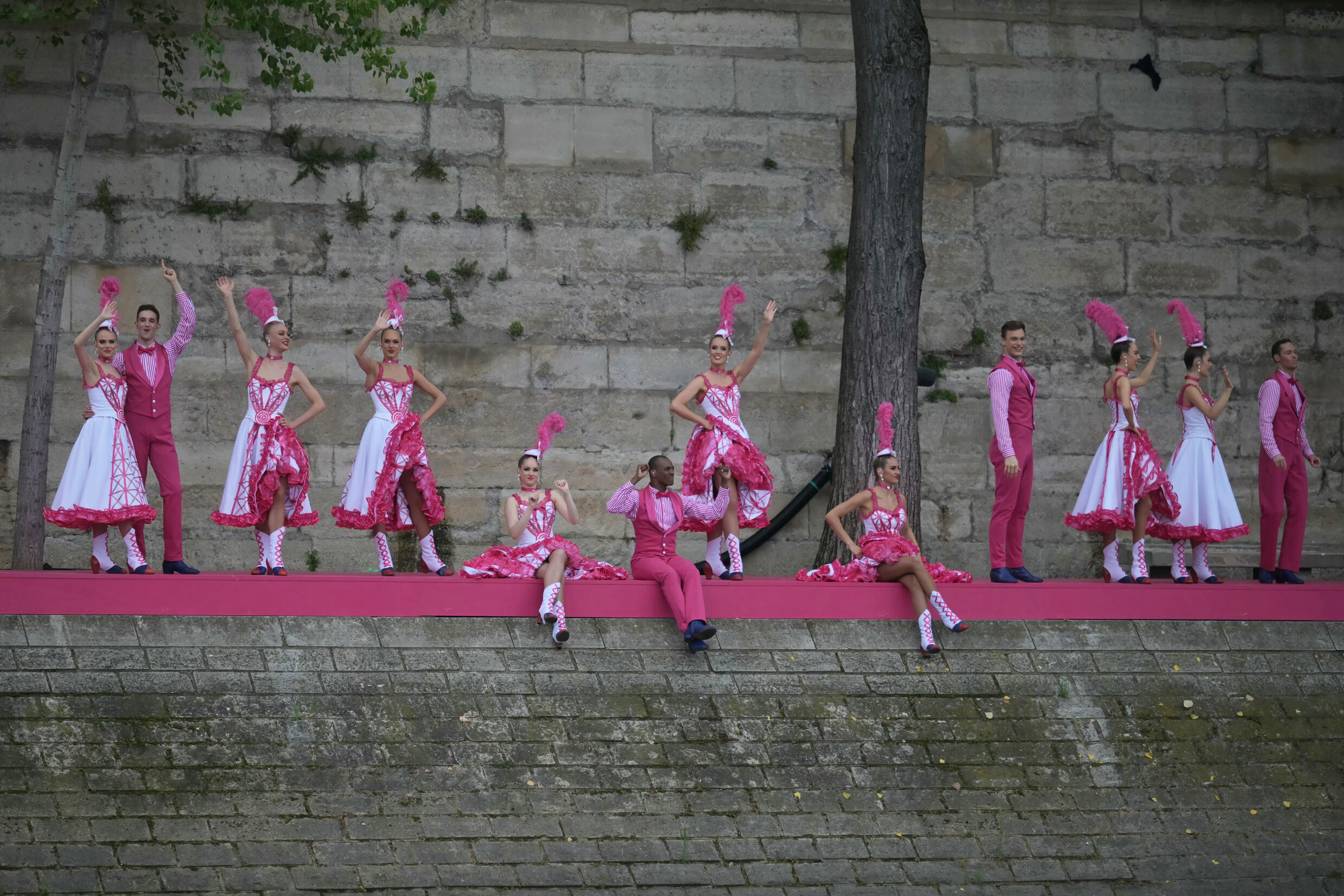 Bailarines de cancan saludan desde la isla de San Luis junto al Sena al paso del barco de Brasil en la ceremonia de apertura de los Juegos Olímpicos de París, el 26 de julio de 2024