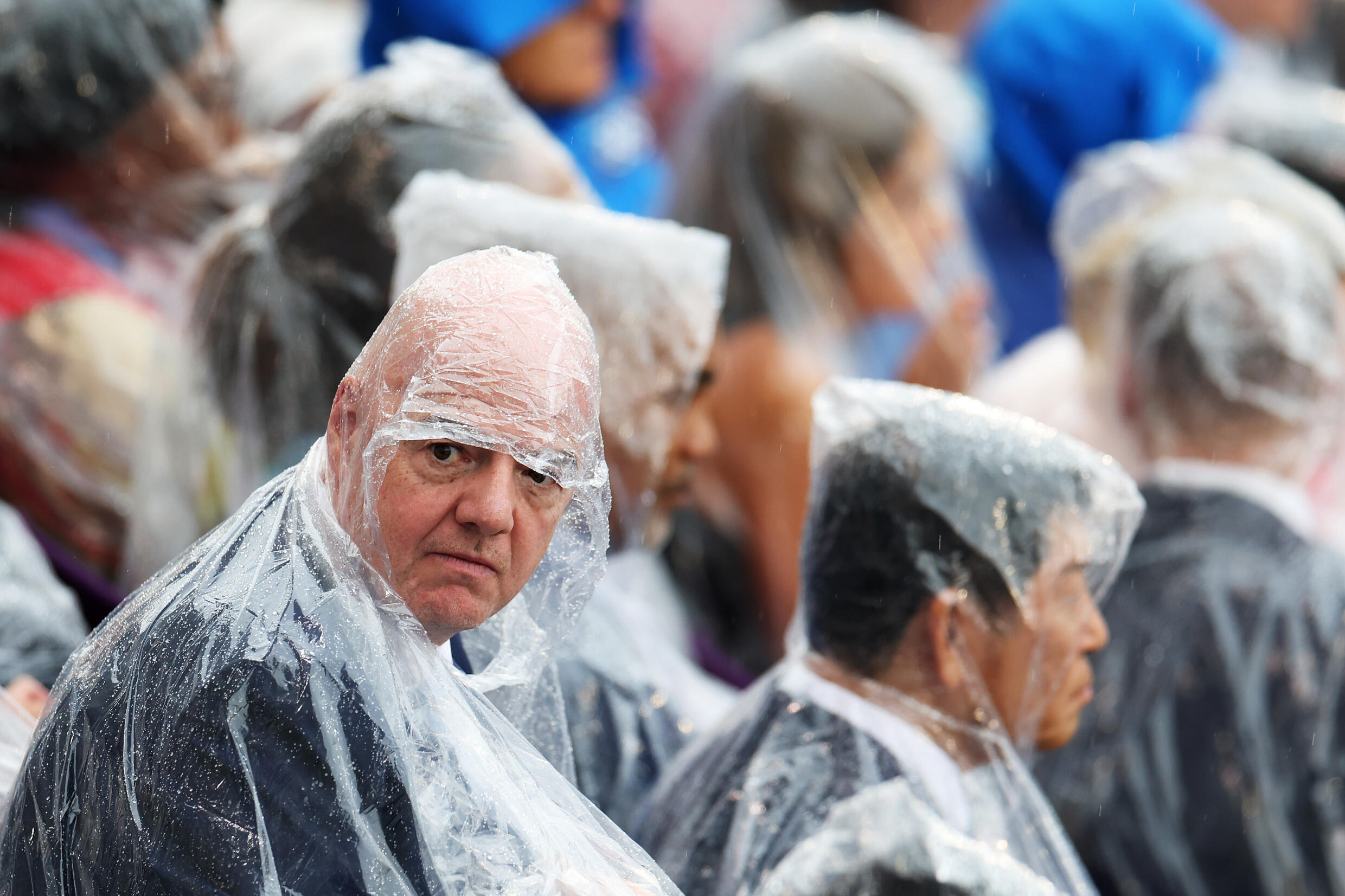 El presidente de la FIFA, Gianni Infantino, se cobija de la lluvia con un chubasquero durante la ceremonia de apertura de los Juegos Olímpicos de París, junto al río Sena, el 26 de julio de 2024.