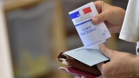 A woman holds a voting envelope and her electoral card at a polling station in Nantes, western France.