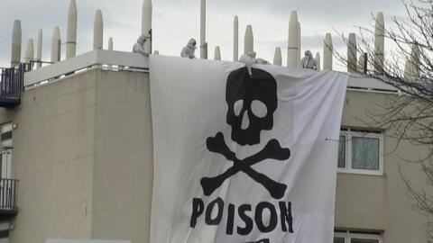 This image grab taken from AFPTV footage shows Extinction Rebellion and Youth for Climate activists deploying a giant banner depicting a skull and bones, bearing the message "Poison", atop a structure inside the Arkema chemical plant after they entered the site to protest against pollution caused by polyfluoroalkyl substances (PFAS), in Pierre-Benite, south of Lyon on 2 March, 2024.