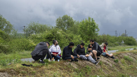 Migrants eat near a makeshift camp close to Dunkirk, in northern France, on Tuesday, May 14, 2024.