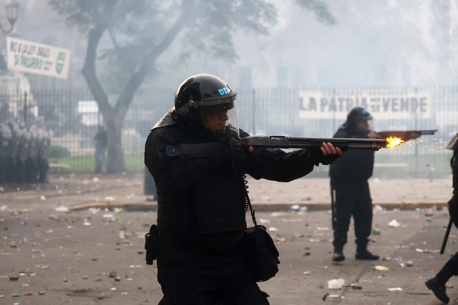 Policial dispara sua arma durante confrontos com manifestantes do lado de fora do Congresso Nacional, em Buenos Aires — Foto: TOMAS CUESTA / AFP