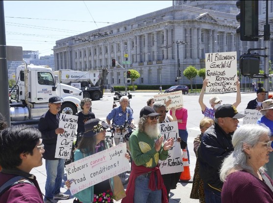 Manifestantes protestam do lado de fora de onde a Comissão de Serviços Públicos da Califórnia realizava uma audiência sobre carros autônomos