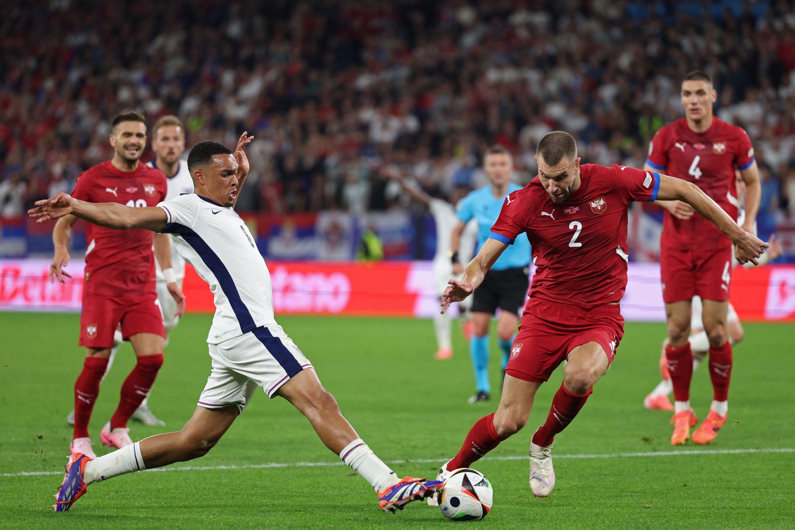 O zagueiro inglês # 08 Trent Alexander-Arnold luta pela bola com o zagueiro sérvio # 02 Strahinja Pavlovic durante a partida de futebol do Grupo C da UEFA Euro 2024 entre Sérvia e Inglaterra na Arena AufSchalke em Gelsenkirchen — Foto: Adrian DENNIS / AFP