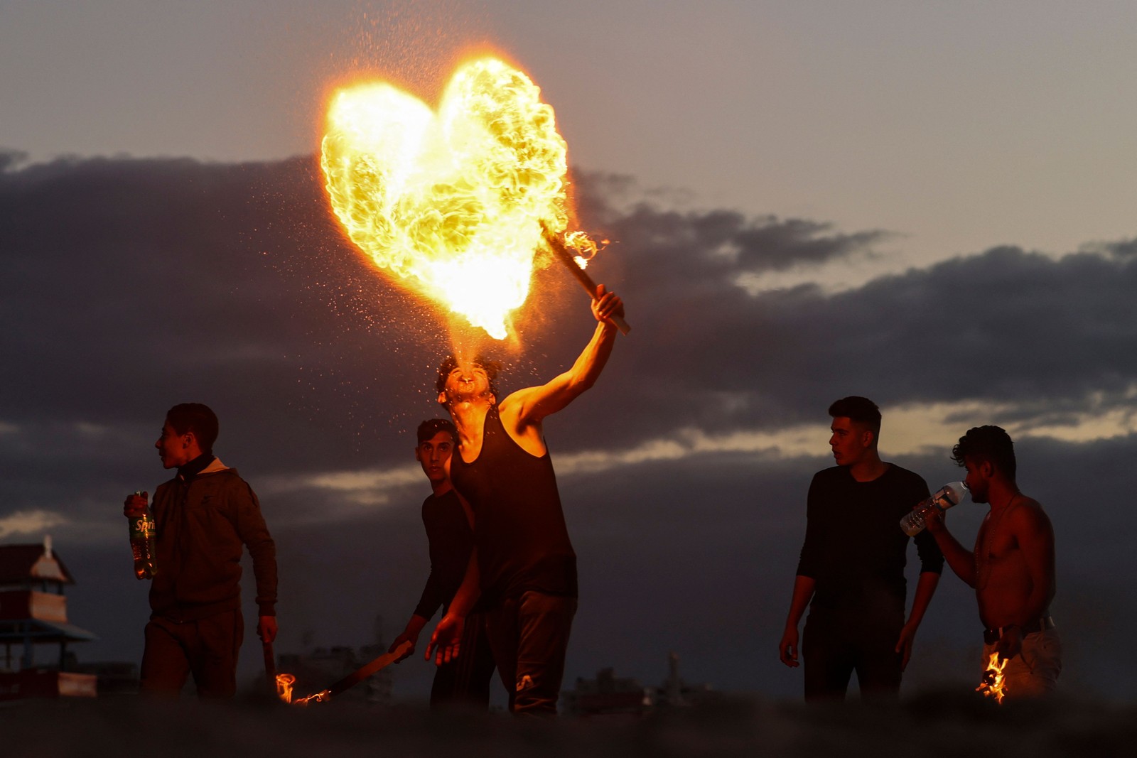 Jovens palestinos formam um coração usando fogo — Foto: MOHAMMED ABED / AFP