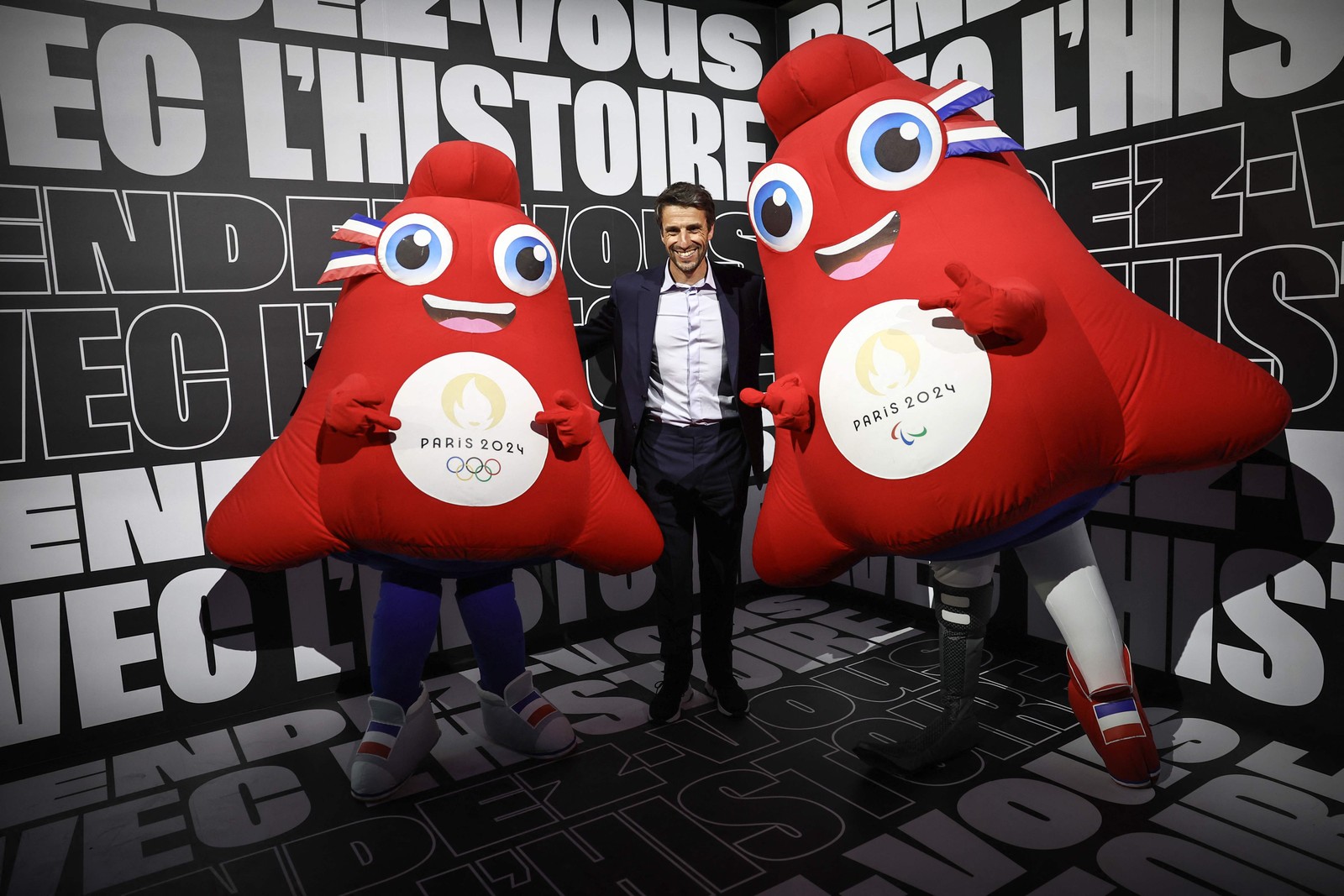 O presidente francês do Comitê Organizador dos Jogos Olímpicos e Paralímpicos de Paris 2024, Tony Estanguet, posa com os mascotes de Paris 2024, "os Phryges". O mascote retrata um chapéu e foi escolhido por ser um grande símbolo de liberdade para os franceses. - Foto: Anne-Christine POUJOULAT / AFP