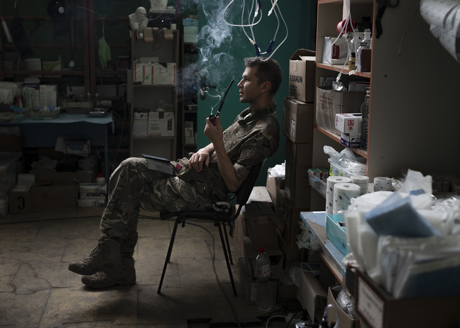 Romashka, chefe de um ponto de estabilização médica na região de Zaporizhzhia, na Ucrânia, fumando um cachimbo após terminar o tratamento de pacientes. Foto: Emile Ducke/The New York Times