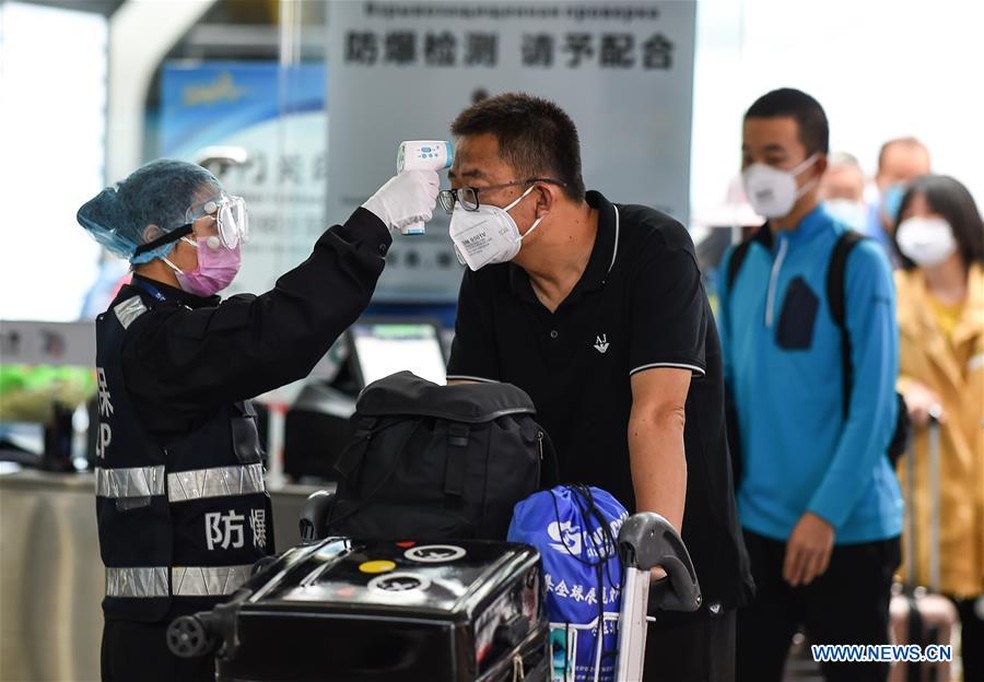 Em aeroporto na China, pessoas usam máscaras e passam por verificação de temperatura como forma de prevenção ao coronavírus — Foto: Divulgação/Xinhua/Pu Xiaoxu