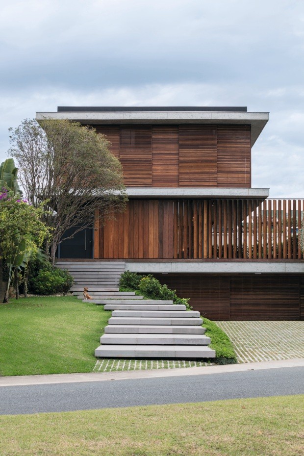 Fachada. É definida pelos planos verticais e horizontais com madeira e concreto em estado bruto. Os degraus de basalto cinza parecem flutuar. Uma jabuticabeira dá as boas-vindas na entrada da casa (Foto: Leonardo Finotti / Editora Globo)