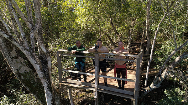 Foto de pessoas em uma ponte com uma floresta atrás.