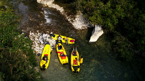 Foto de cima mostra pessoas dentro de canoas à margem de um rio