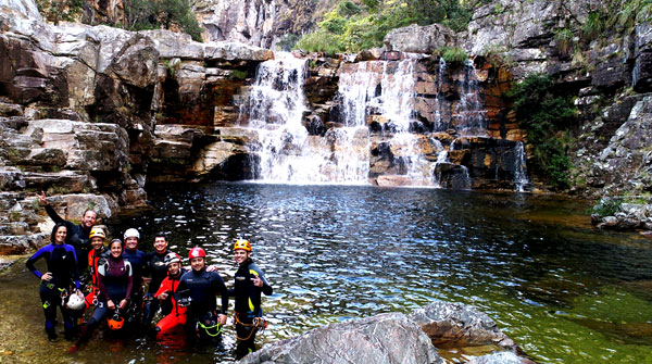 Foto dos apresentadores com um grupo de pessoas e uma cachoeira ao fundo