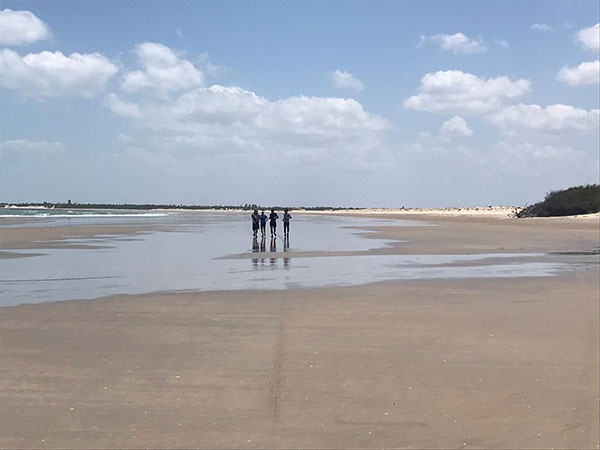 Quarto pessoas distantes correndo em uma praia.