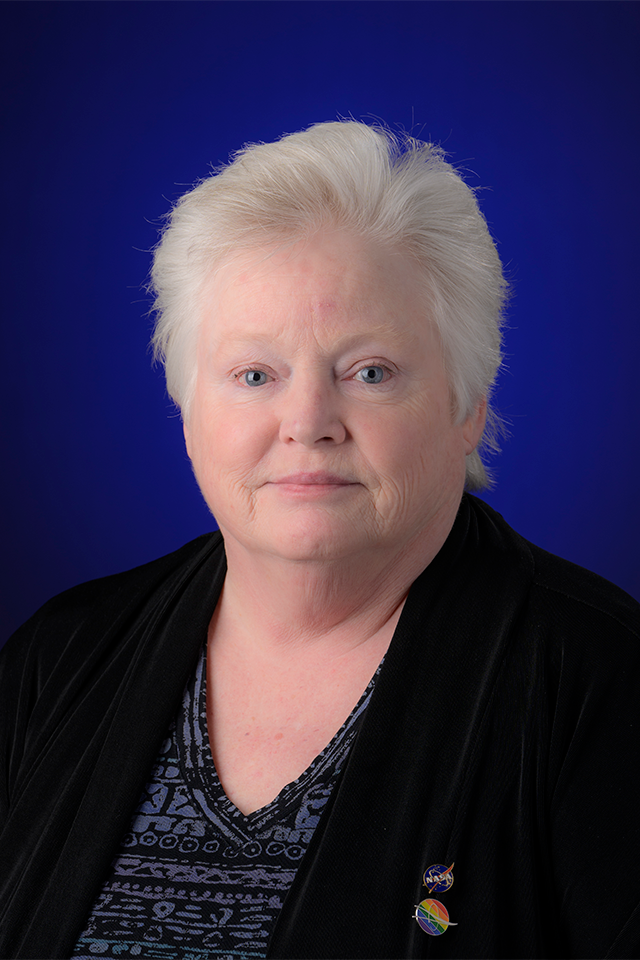 Portrait photo of a woman with short light hair in a dark suit jacket.