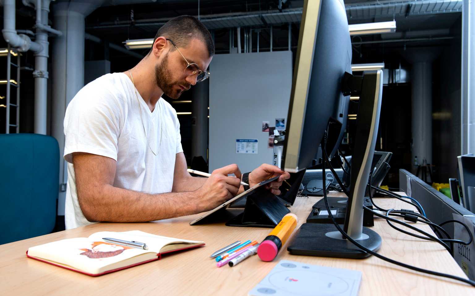 Engineer working in his office at a desktop computer with books and other materials on his desk. He appears engrossed in his work.