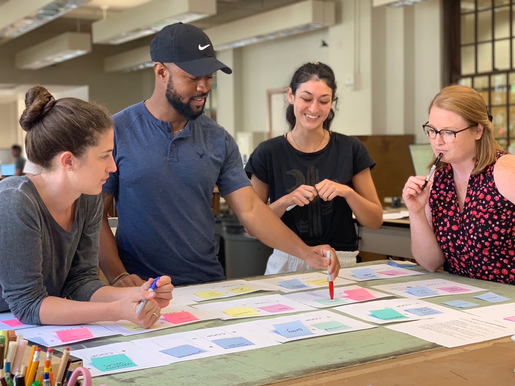 Four students gather over materials on a desk in studio