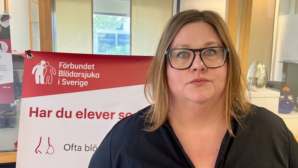 Portrait of a woman in front a sign for the Swedish Bleeding Disorder Society.
