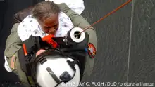 A U.S. Navy Petty Officer retrieves an evacuee of Hurricane Katrina from a rooftop onto a helicopter.