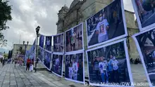 The DW Akademie- suported photo project hangs in a busy square in front of a church.