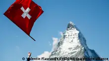 ARCHIV - 14.09.2014, Schweiz, Zermatt: Ein Fahnenwerfer mit der Schweizer Flagge in Aktion vor der Kulisse des Matterhorns. Tolle Natur, Klasse-Schokolade: Die Schweiz hat in Umfragen einen guten Ruf. Das Image bröckelt aber. (zu dpa Das Image der Schweiz bröckelt) Foto: Valentin Flauraud/KEYSTONE/dpa +++ dpa-Bildfunk +++