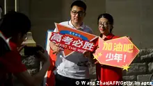 A student holding a poster reading Gao Kao, must win poses for a picture with a volunteer before he enters a school on the first day of China's national college entrance examination, known as the gaokao, in Beijing on June 7, 2023. (Photo by WANG Zhao / AFP) (Photo by WANG ZHAO/AFP via Getty Images)