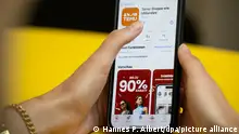 Eine Person hält ein Telefon mit der App Temu in den Händen. (gestellte Szene). Mit seinen Billigangeboten schwimmt der Online-Marktplatz aus China in Deutschland auf einer Erfolgswelle. Keine andere App wird derzeit öfter heruntergeladen. (zu dpa: «Billig-App Temu »)