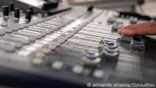 A hand pushes some sliders on a sound mixer