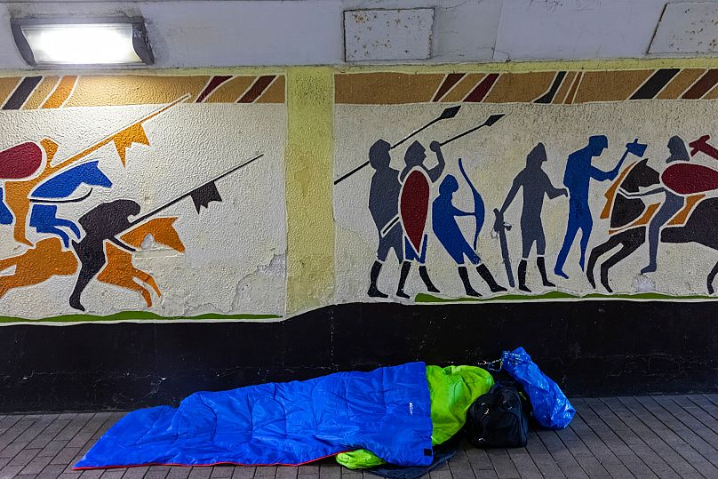 Un vagabundo en Hastings, frente a un mural que representa la invasión normanda de Inglaterra de 1066