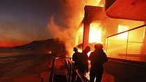 Los Bomberos trabajan desde una cubierta como el Palisades Fire quema una propiedad frente a la playa miércoles, 8 de enero 2025 en Malibú, California.