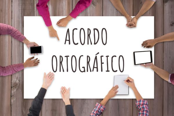 Pessoas reunidas próximo a uma cartolina com o escrito"Acordo Ortográfico".