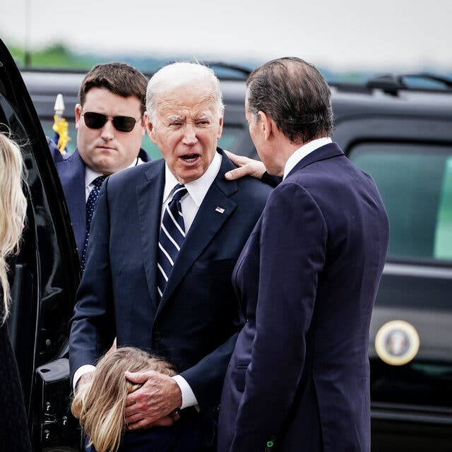 President Biden speaks to Hunter Biden while he comforts a child.