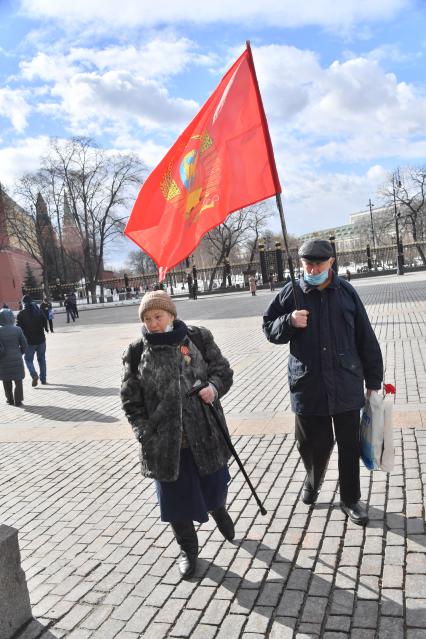 Москва.  Мужчина и женщина с флагом после церемонии возложения венков и цветов к месту захоронения Иосифа Виссарионовича Сталина у Кремлевской стены.