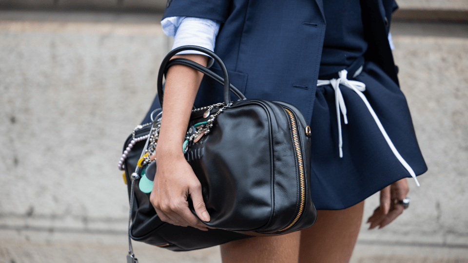 A street style star wearing navy clothes and holding a big black handbag