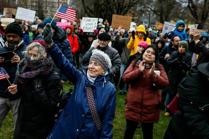 Eine protestierende Menschenmenge, eine Frau hält eine US-Fahne in der Hand