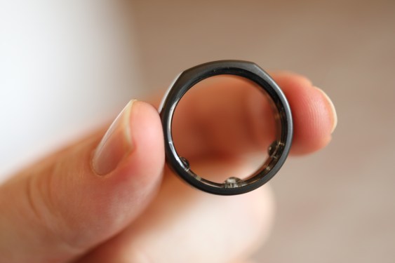 person holding Oura ring between thumb and forefinger