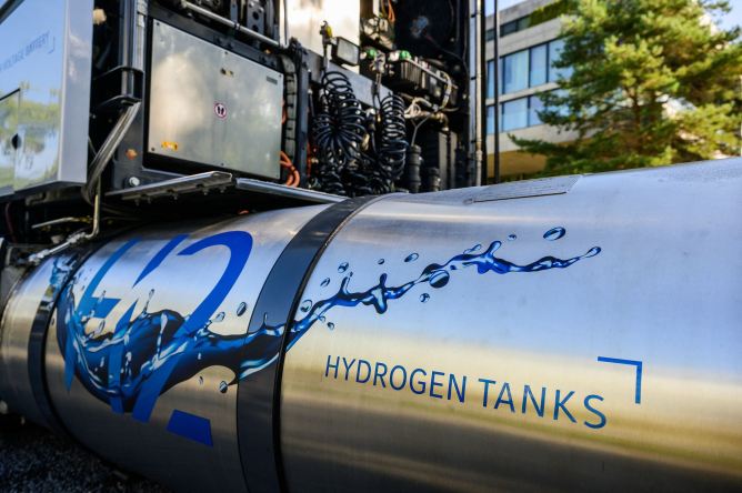 A hydrogen tank sits attached to an idle semi truck.