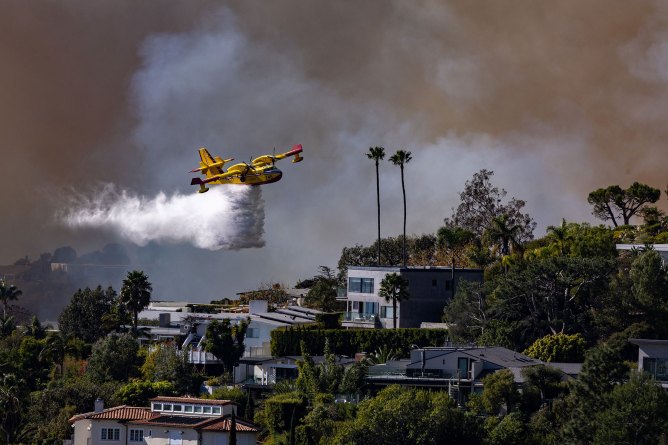 Pacific Palisades, CA - January 07: A Super Scooper plane drops water on the Palisades fire on Tuesday, Jan. 7, 2025 in Pacific Palisades, CA. (Brian van der Brug / Los Angeles Times via Getty Images)