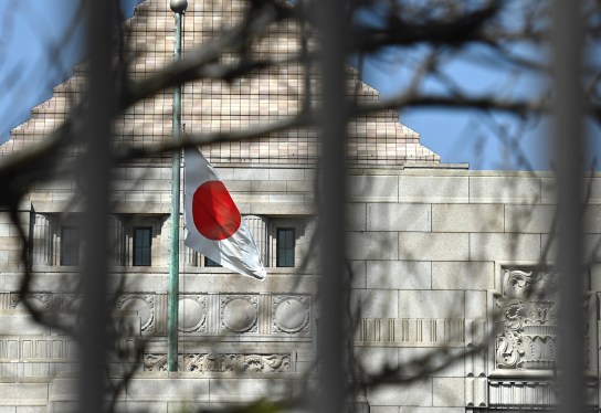 a Japanese flag fluttering in the wind in the distance in front of a building in Tokyo