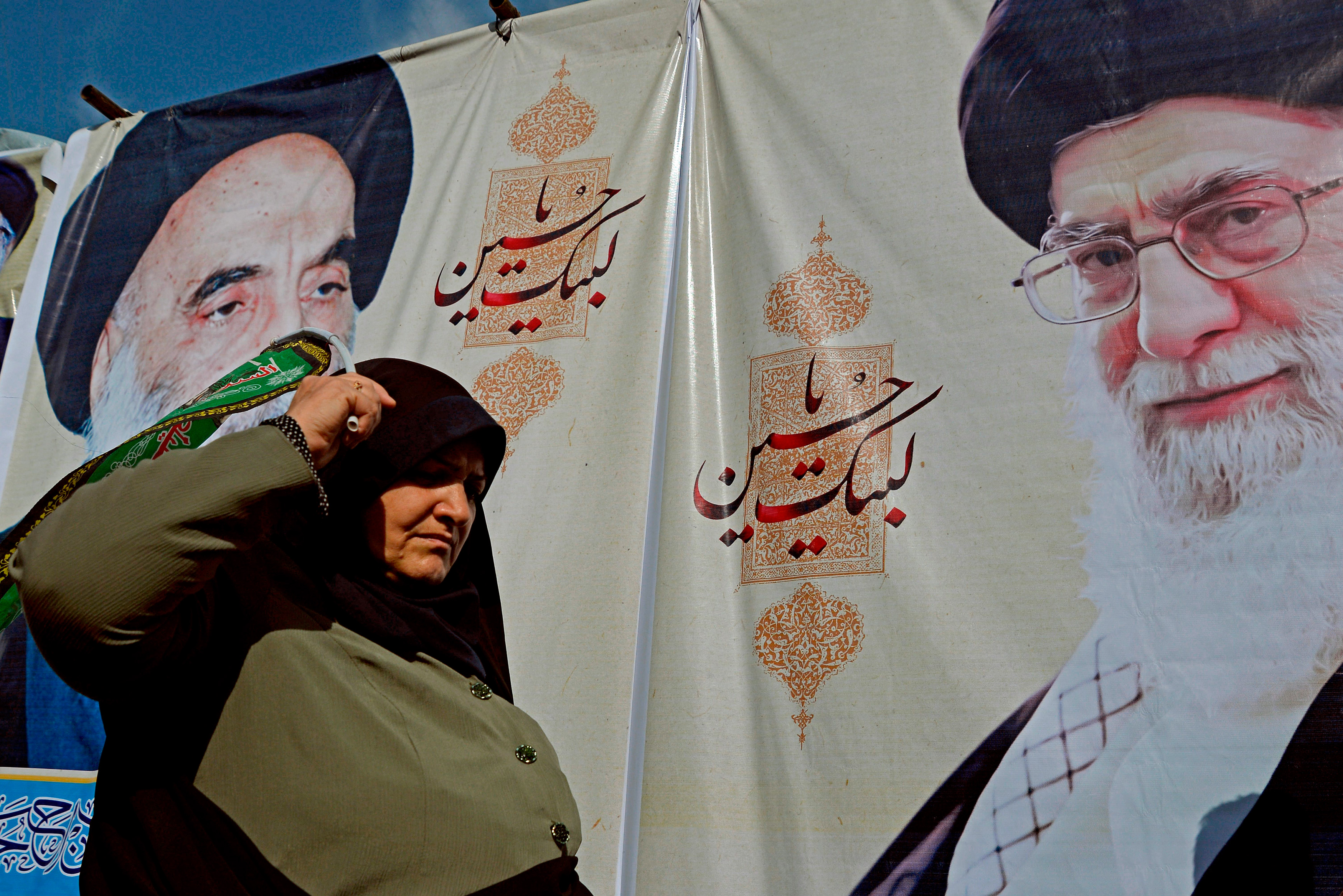 A Shiite Muslim pilgrim walks in front of posters of Iran's Supreme Leader Ayatollah Ali Khamenei (R) and the spiritual leader of the Shiite community Grand Ayatollah Ali Sistani, during a procession from the holy Iraqi city of Najaf to the central shrine city of Karbala on October 12, 2019, ahead of the Arbaeen religious festival. - Shiite Muslim pilgrims continued to converge to the holy Iraqi cities of Najaf and Karbala ahead of Arbaeen, which is an observance that peaks on the 40th day after Ashura, commemorating the seventh century killing of the Prophet Mohammed's grandson Imam Hussein. (Photo by Haidar HAMDANI / AFP) (Photo by HAIDAR HAMDANI/AFP via Getty Images)