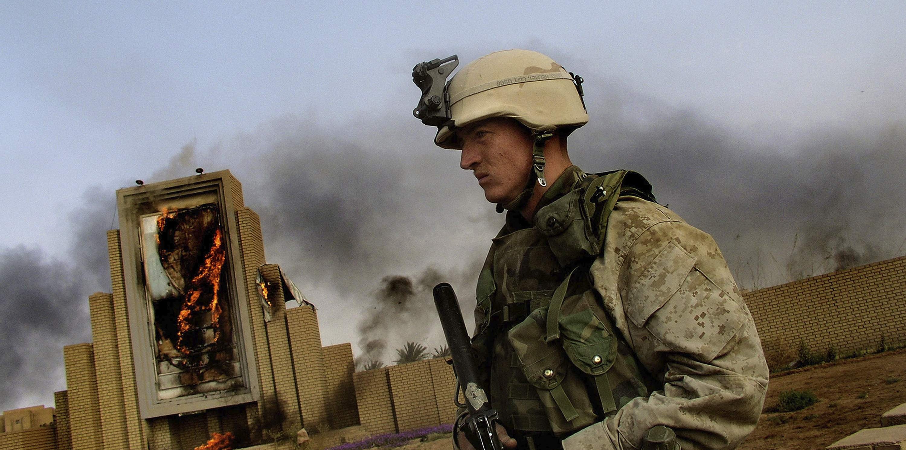 IRAQ. Baghdad. A US Marine in front of a burning poster of Saddam Hussein. April 10 2003.