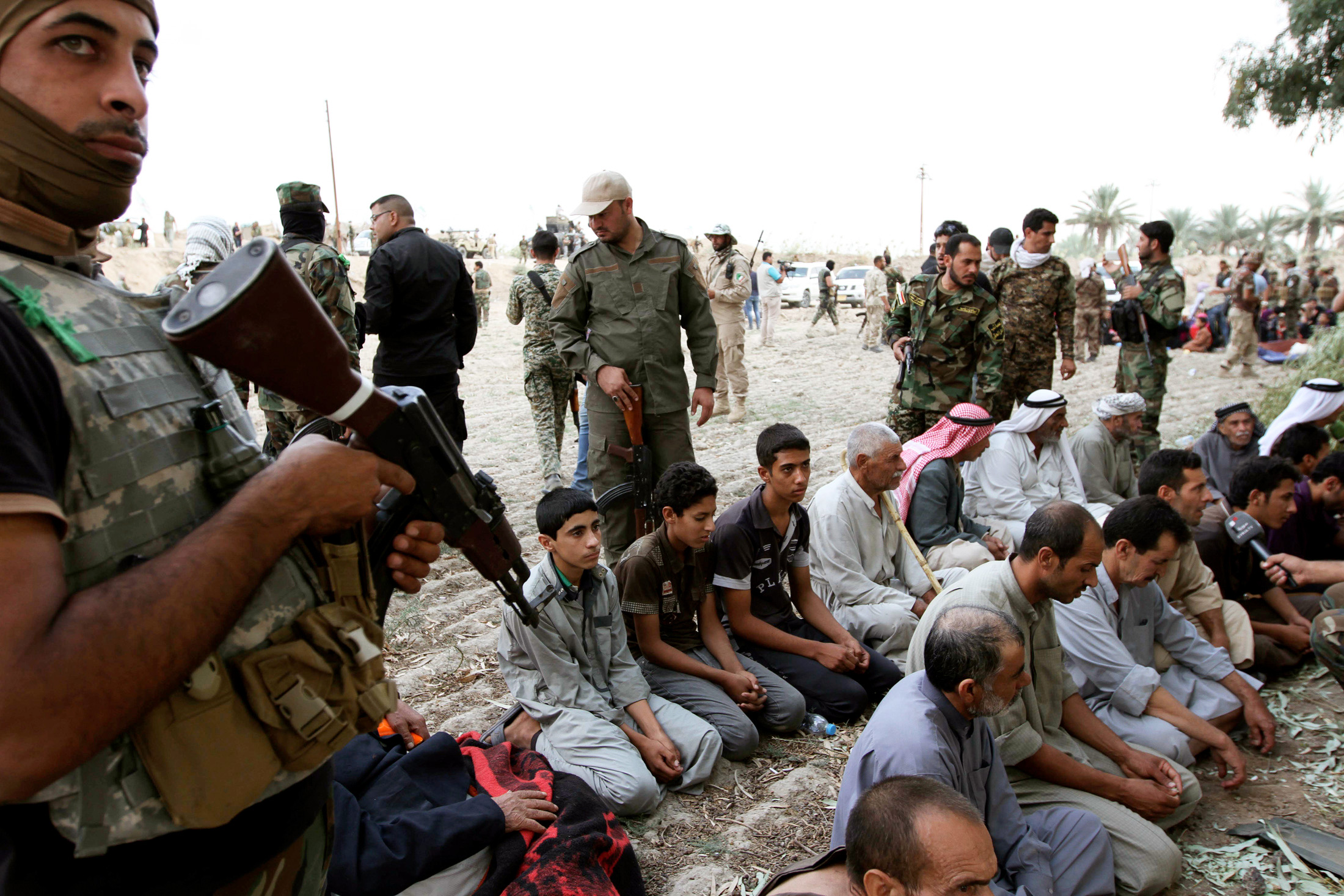 Iraqi families sit after surrendering to Shi'ite fighters and Iraqi Army after they took control of Jurf al-Sakhar from Islamist State militants, October 27, 2014. The families, who were in militant-held areas, surrendered to the army to be transported to safe areas and escape clashes between militants and Iraqi security forces, according to the Iraqi Army and the fighters. Picture taken October 27, 2014. REUTERS/Mahmoud Raouf Mahmoud (IRAQ - Tags: CIVIL UNREST POLITICS CONFLICT MILITARY SOCIETY TPX IMAGES OF THE DAY) - GM1EAAS1L0D01