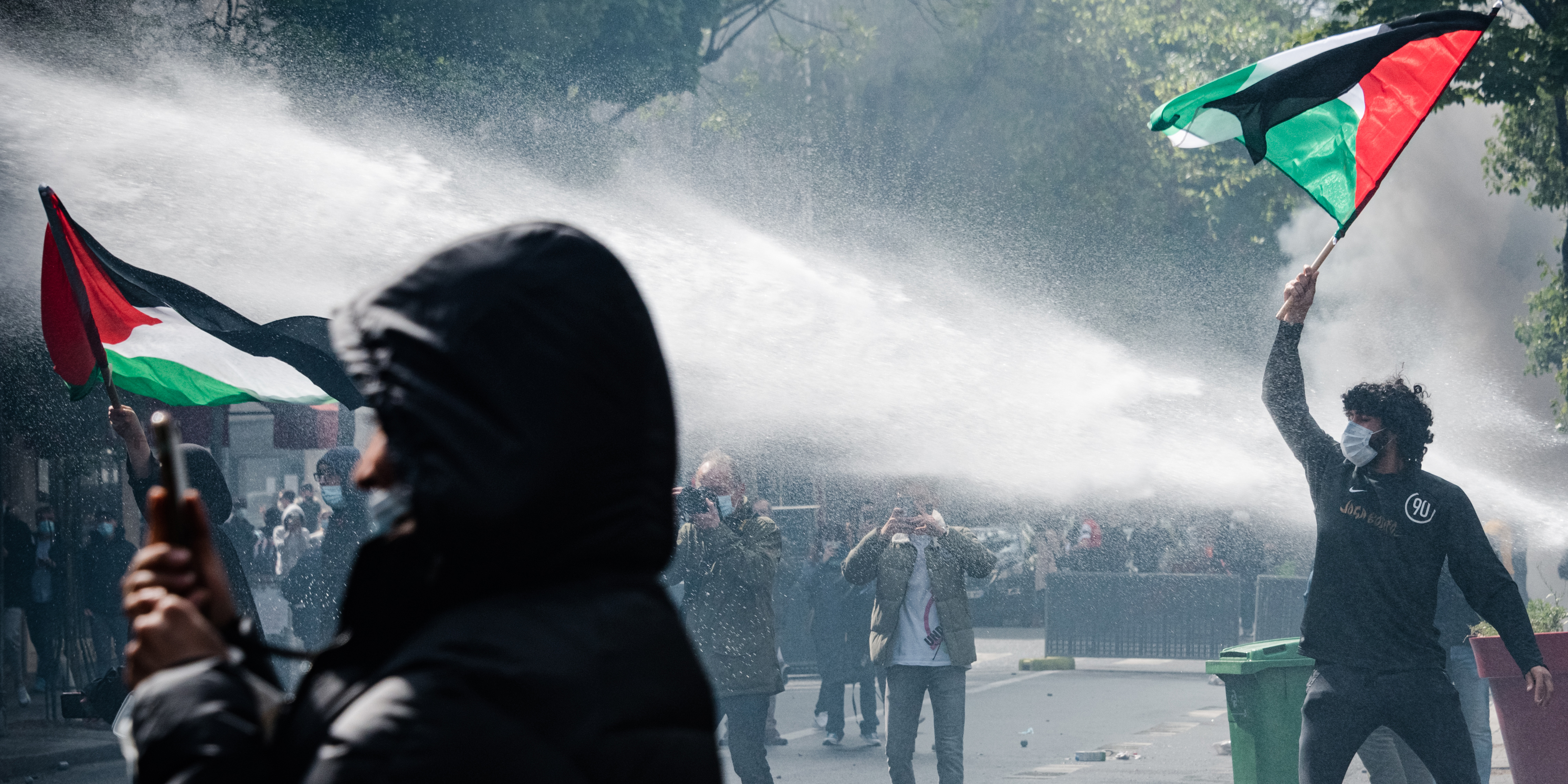 A pro-Palestinian demonstrator carrying a Palestinian flag was shot at by police with a water cannon on 15 May 2021 when, at the call of numerous organisations, a demonstration in support of the Palestinian people was organised in the Barbès district of Paris following the recent tensions in the Middle East between Israel and Palestine, both in the Gaza Strip and the West Bank. Due to fears of outbursts, the march was banned by the Prefecture, creating numerous scenes of violence between demonstrators who had defied the ban and the police who were deployed in large numbers to prevent the slightest beginning of the rally. (Photo by Samuel Boivin/NurPhoto via Getty Images)