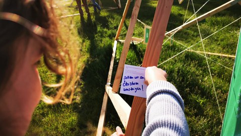 jemand steckt Wunscharte an Green-Office-Installation an