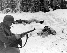 SC 198859 - Pfc. Frank Vukasin, Great Falls, Mont., stops to load clip in rifle while advancing in snow-covered front-line sector at Houffalize, Belgium. (52524439514).jpg