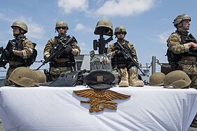 Visit, board, search, and seizure (VBSS) sailors assemble around a memorial to Keating during the Memorial Day ceremony aboard the Arleigh Burke-class destroyer USS William P. Lawrence.