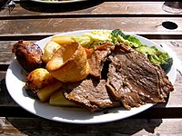 Un Sunday roast inglés con roast beef, papas asadas, vegetales y Yorkshire pudding