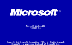 Startbildschirm von Windows 2.11 (deutsch): im oberen Bildteil groß das „neue“ (noch aktuelle) Logo “Microsoft (R)” (kursiv), in der Mitte in kleinerer „Computerschrift“ die Versionsangaben und am unteren Bildschirmrand die Urheberrechtsvermerke; alles zentriert gehalten