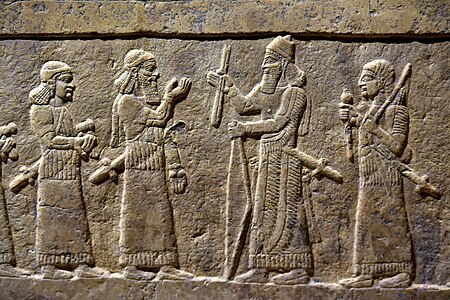 Bas-relief de l'estrade de la salle du trône de Fort-Salmanazar, face sud : Salmanazar III reçoit le tribut du chaldéen Musallim-Marduk du Bit-Amukkani. Musée national d'Irak.